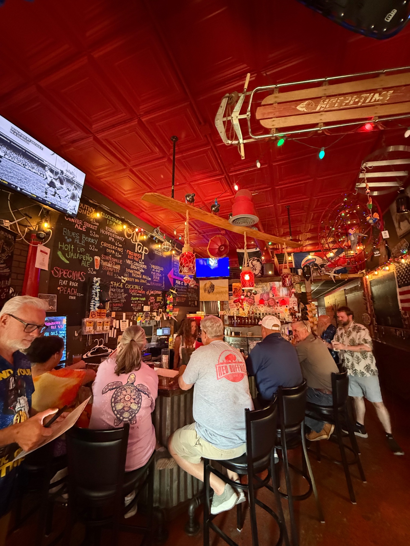 Guests at the Red Buffalo Brewing Co. bar under the glowing red tin ceiling